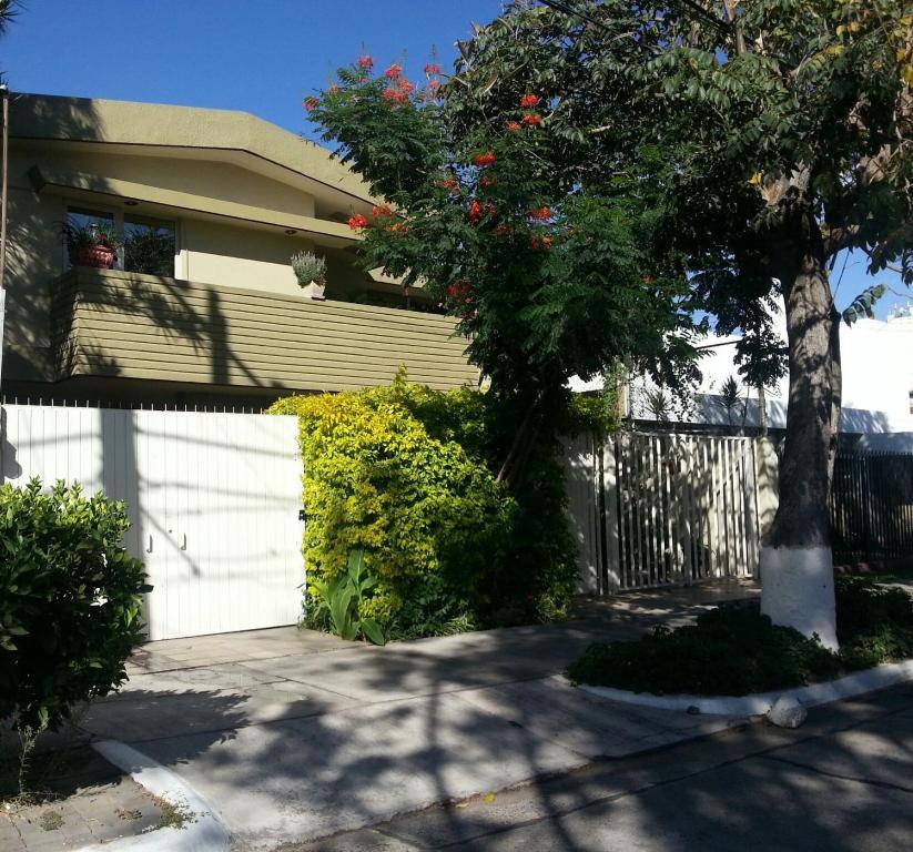 a house with a white fence and a tree at Dickinson Guest House, Guadalajara Expo in Guadalajara