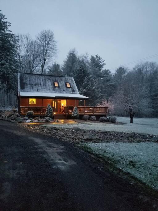 a cabin with a snow covered roof and a truck parked in front at Cozy Cabin By the Slopes in McHenry
