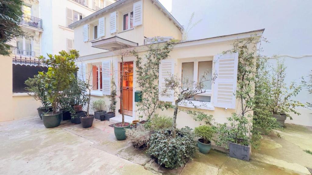 une maison avec un tas de plantes en pot devant elle dans l'établissement Small duplex house in Batignolles, à Paris