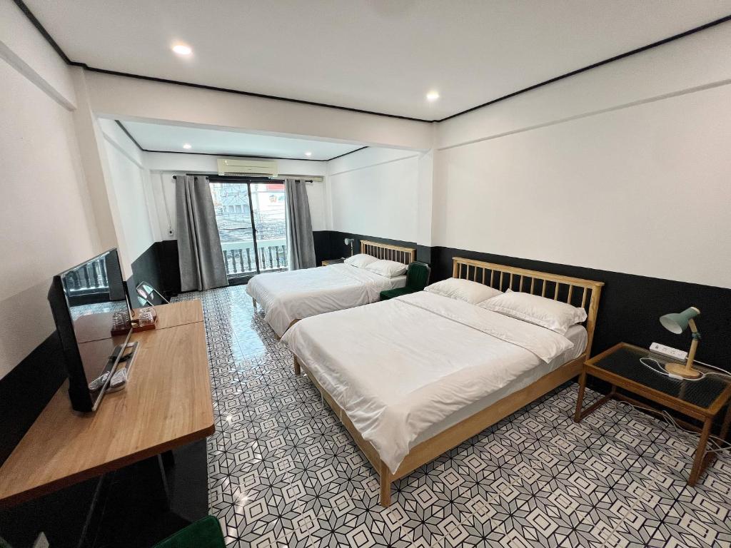 a hotel room with two beds and a desk and a desk at Years 1981 in Bangkok