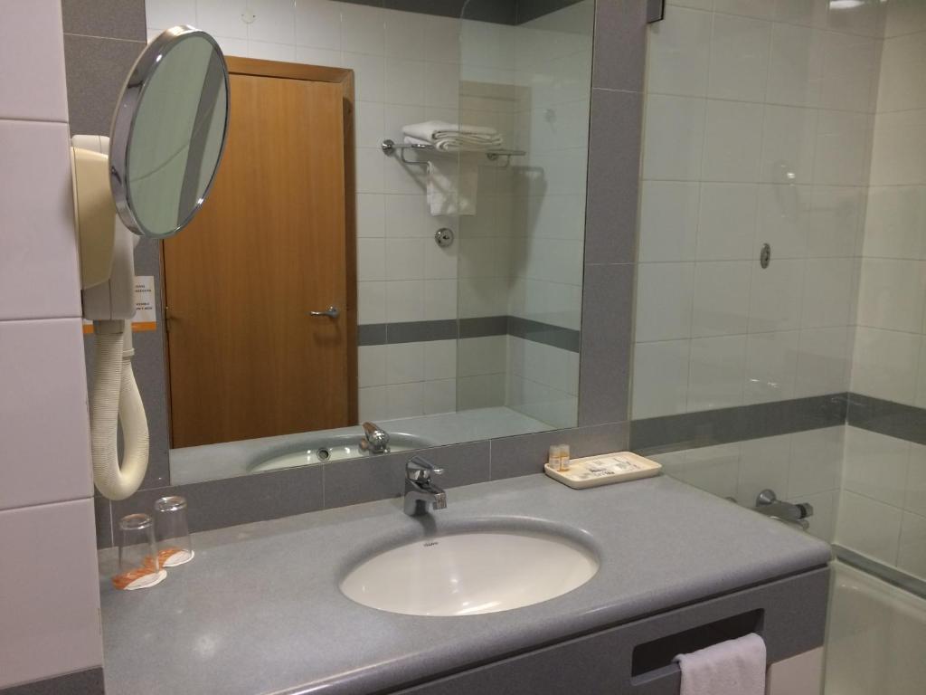 a bathroom with a sink and a mirror at Riviera Hotel in Carcavelos