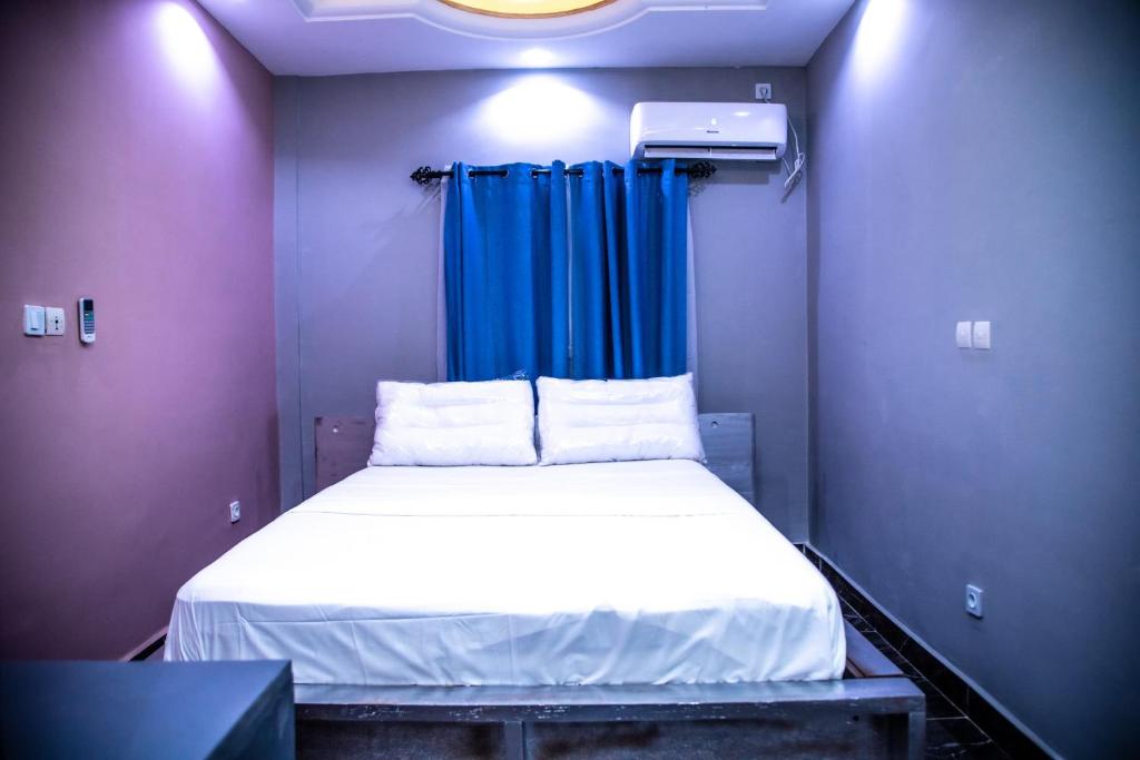 雅温得Luxuria Inn yaounde的一张位于小房间的床,里面配有蓝色窗帘