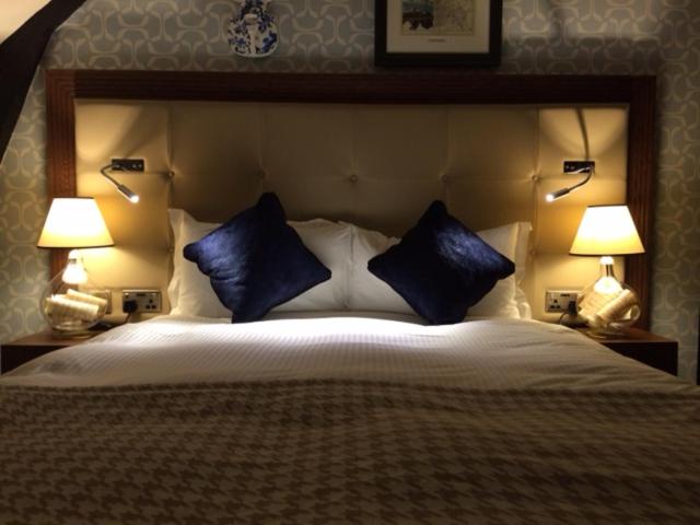 a bedroom with a large bed with blue pillows at The Crown Wetherspoon in Worcester