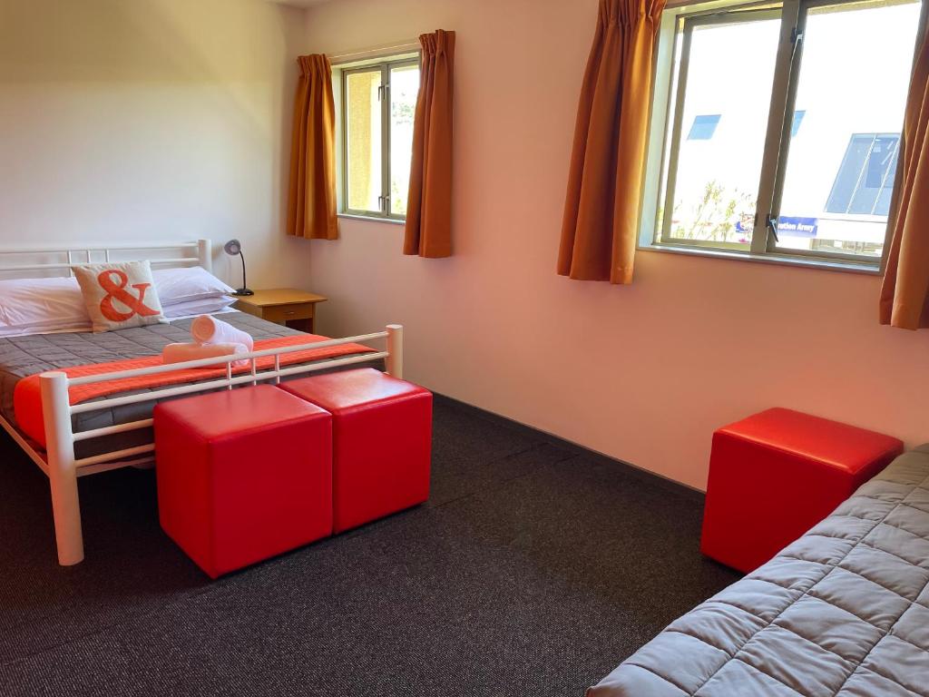 a bedroom with a bed and two red ottomans at YHA Nelson in Nelson