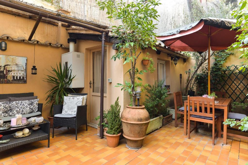 un patio con mesa, sillas y plantas en Malva, en Roma