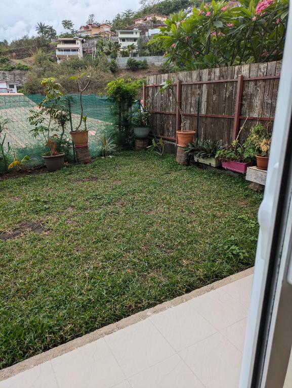 a backyard with plants and a fence at N'JOK Papeete in Papeete