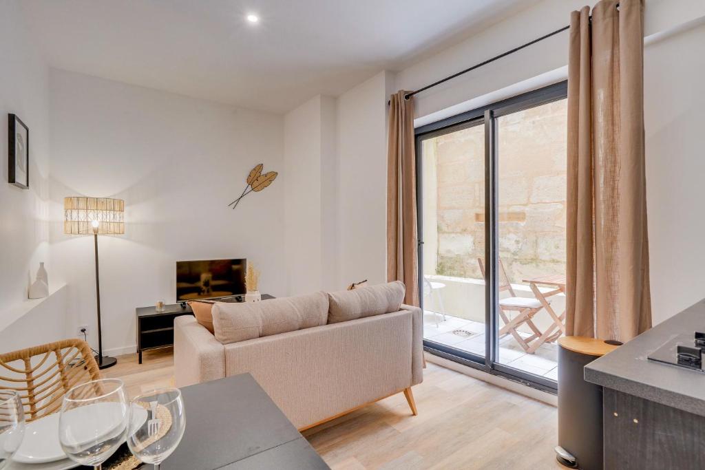 un salon avec un canapé et une grande fenêtre dans l'établissement MDOR - Le Vendange - Plein coeur de Bordeaux, à Bordeaux