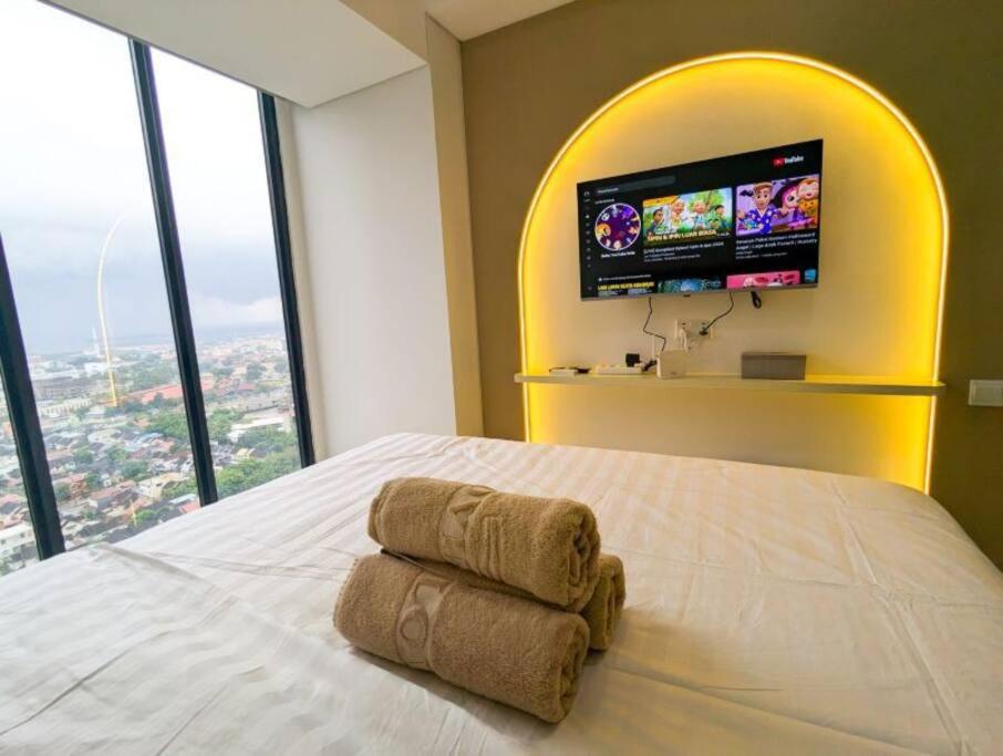 Un dormitorio con una cama con un televisor en la pared. en Lovina 2203 Studio at Pollux Meisterstadt, en Batam Centre