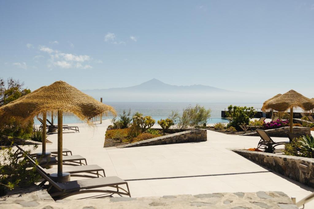 a resort with chairs and umbrellas and the ocean at BANCAL HOTEL and SPA in San Sebastián de la Gomera
