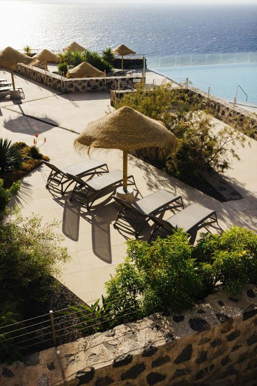 a group of chairs and an umbrella on a beach at BANCAL HOTEL and SPA in San Sebastián de la Gomera