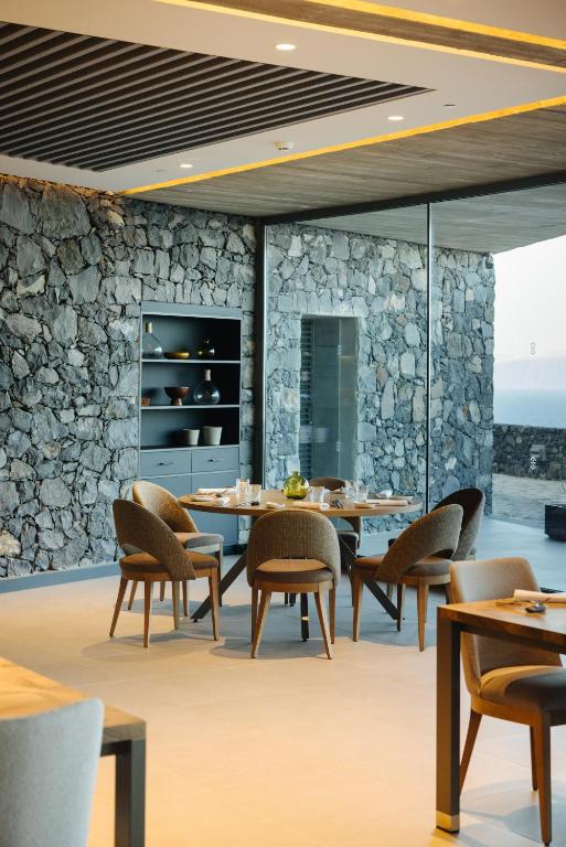 a dining room with tables and chairs and a stone wall at BANCAL HOTEL and SPA in San Sebastián de la Gomera