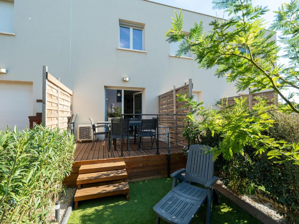 une cour arrière avec une terrasse en bois avec une table et des chaises dans l'établissement La Dune 75 - Villa 3P6, à Valras-Plage