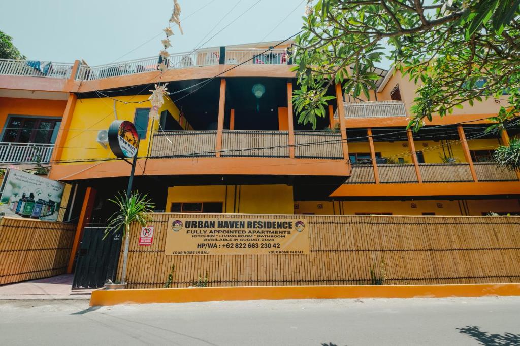 a yellow building with a sign in front of it at Urban Haven Residence in Sanur