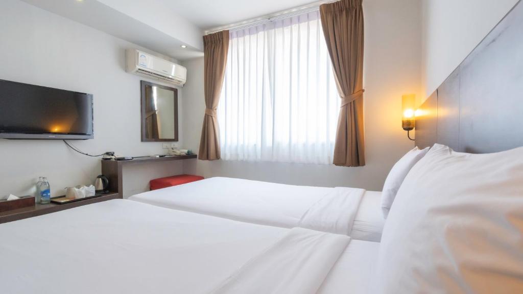 a hotel room with two beds and a television at Pas Cher Hotel de Bangkok in Bangkok