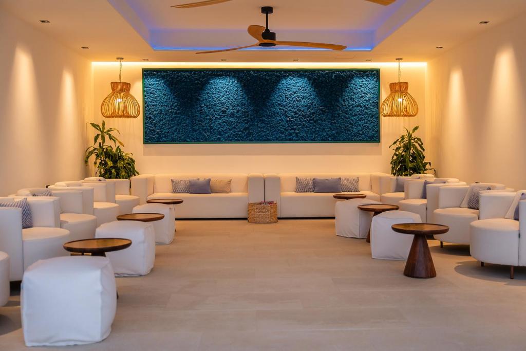 a room with white couches and tables and a painting at Royal Marina Suites Boutique Hotel - Adults Only in Puerto Calero