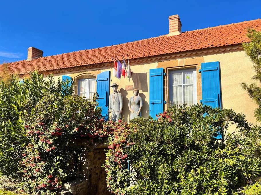 2 personnes debout sur la terrasse couverte d'une maison avec volets bleus dans l'établissement Propriété historique La Joséphine 1828, à La Barre-de-Monts
