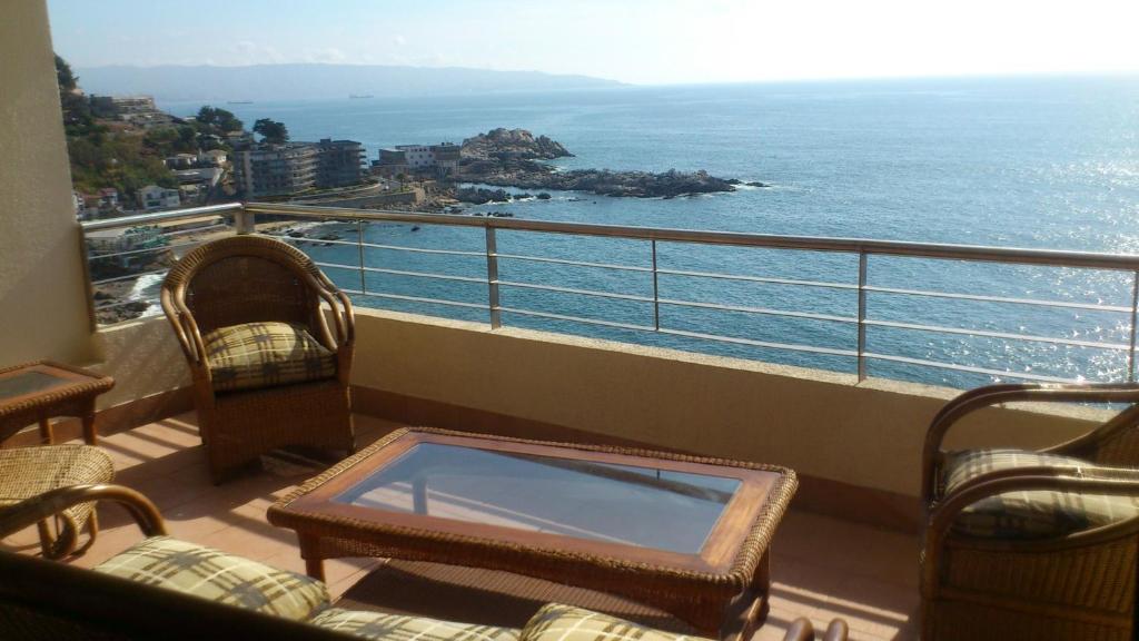 a balcony with chairs and a table and the ocean at On The Beach Apartment in Viña del Mar