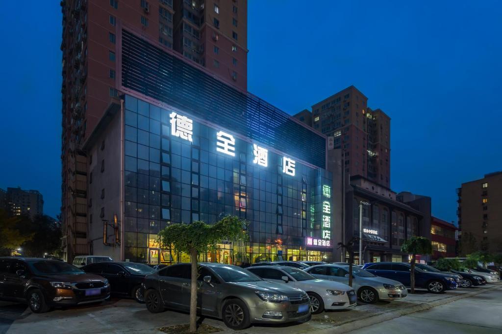 北京Dequan Hotel chaoyang high speedtrain of China Branch的建筑物前停放汽车的停车场