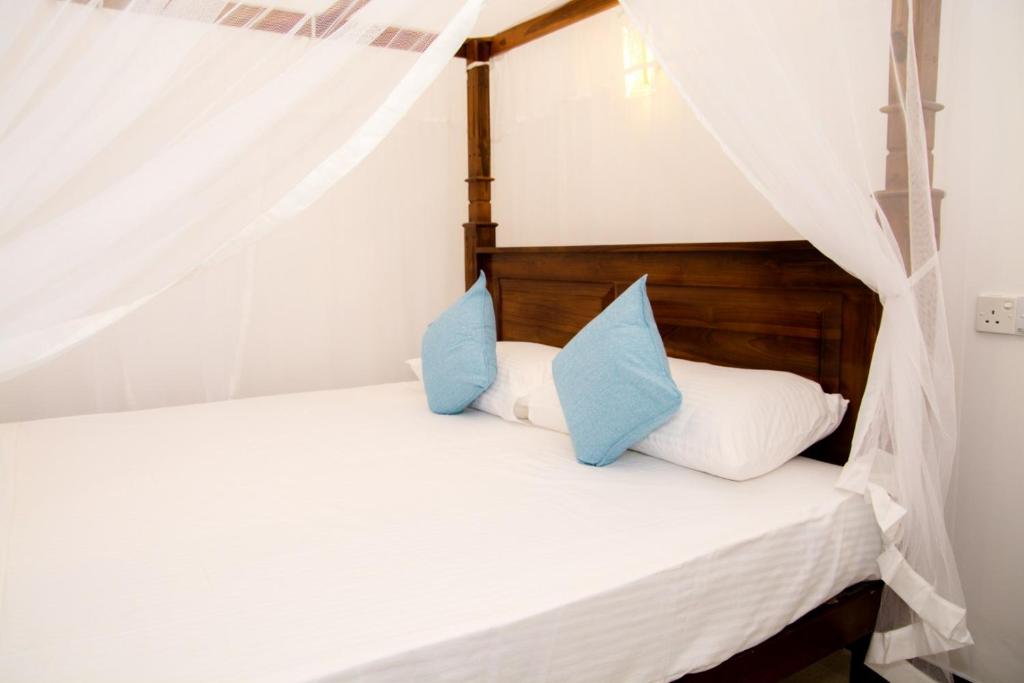 a bedroom with two beds with blue pillows at Samanmali Apartment in Unawatuna