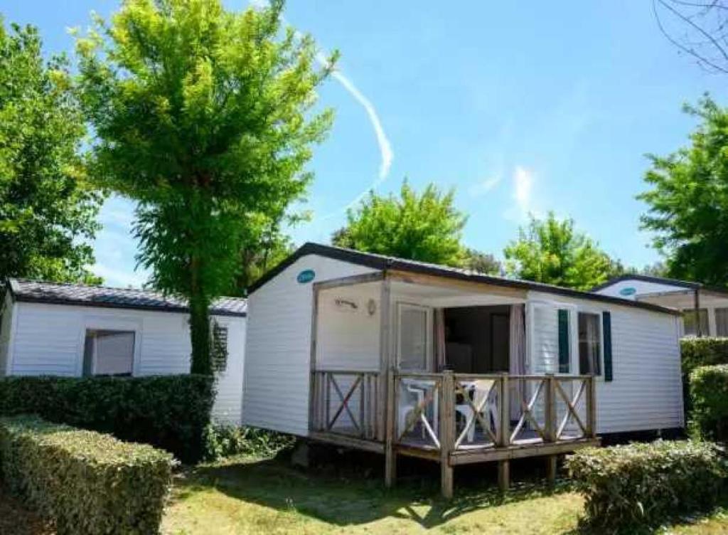 une petite maison blanche avec une véranda et des arbres dans l'établissement Camping 5 étoiles - Piscine - eeaiba, à Saint-Georges-dʼOléron