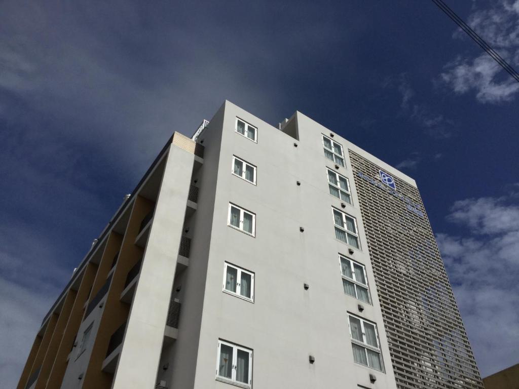 a tall white building with a sky in the background at Hotel Peace Island Miyakojima in Miyako Island