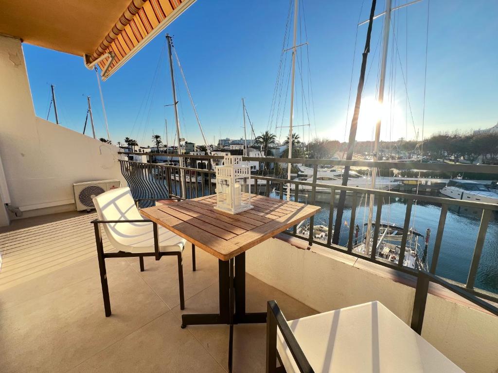 a wooden table and chairs on a balcony with a boat at Estudio Frente al Canal con Terraza in Empuriabrava