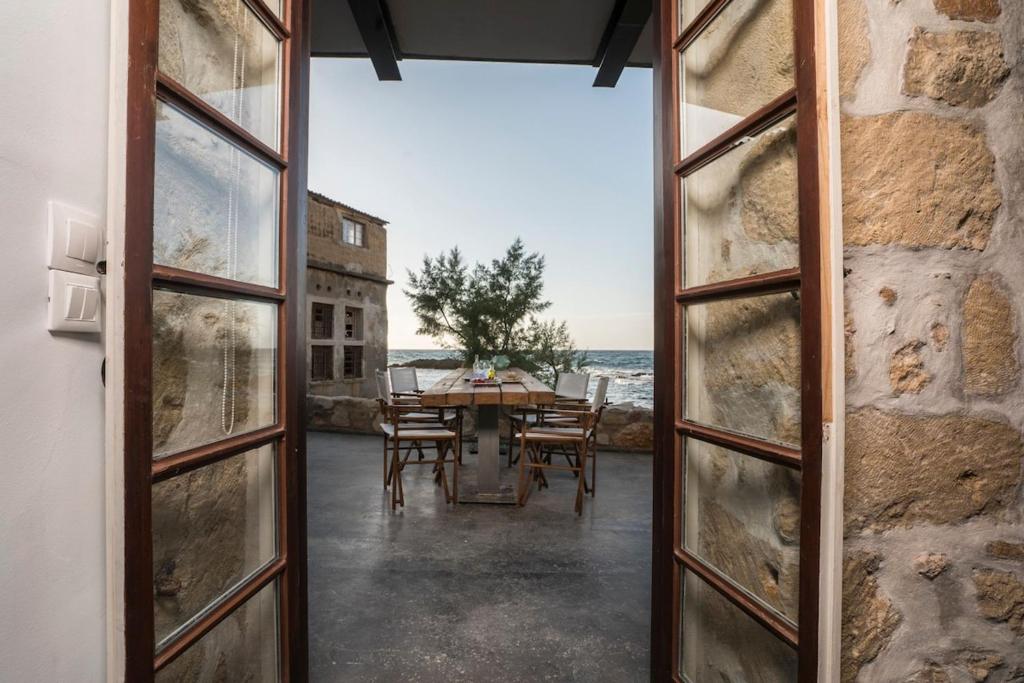 an open door to a patio with a table and chairs at kito- transformed house on the water's edge in Chania