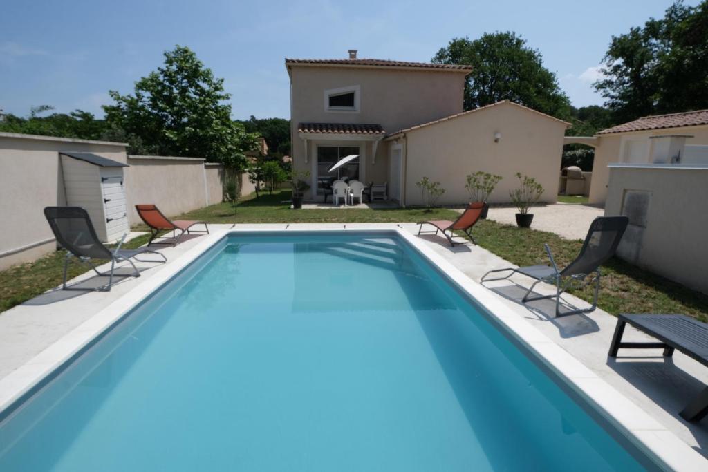une piscine avec des chaises et une maison dans l'établissement very pleasant villa with private swimming pool, in a residential area near the center of saint-rémy-de-provence - 8 people, à Saint-Rémy-de-Provence