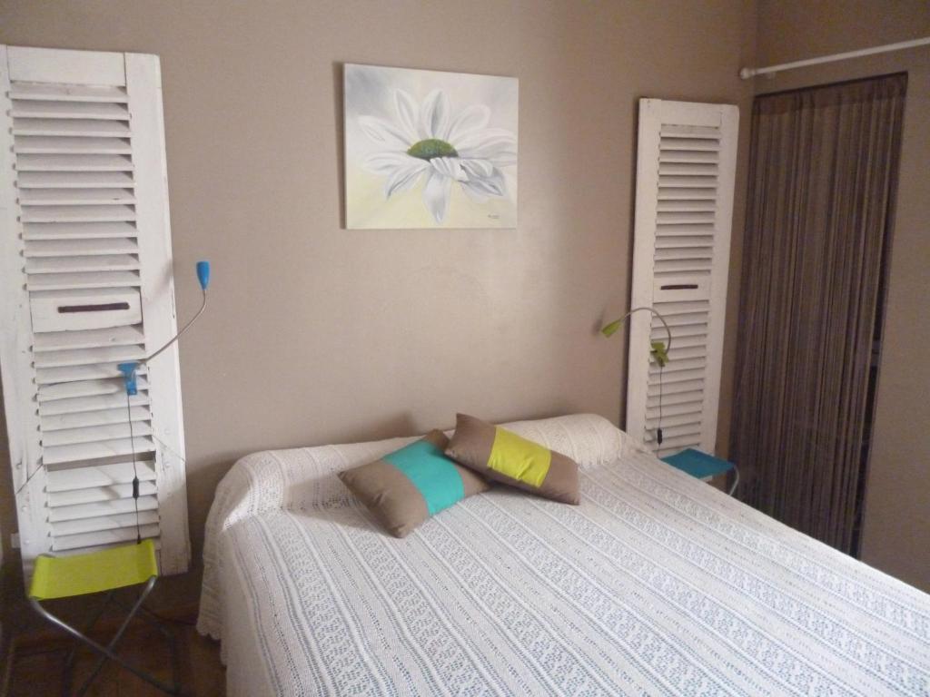 a bedroom with a bed with two white shutters at Chambres d'Hôtes La Rose des Vents in Ginestas