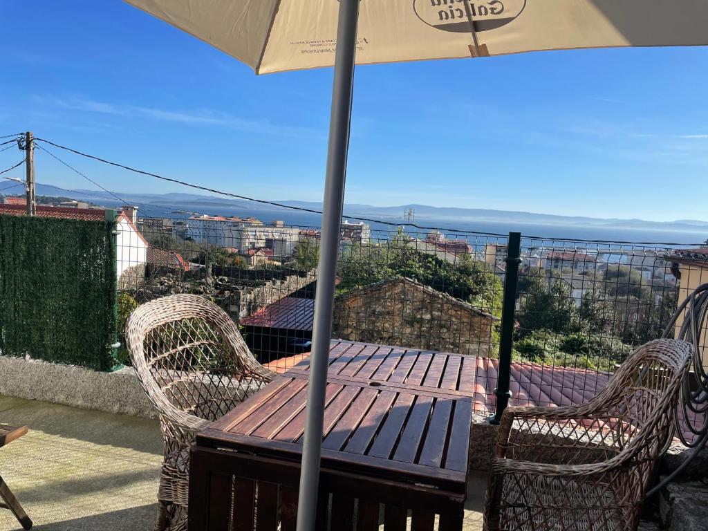 einen Tisch und Stühle mit Sonnenschirm auf dem Balkon in der Unterkunft Mobilhome en Ribeira con vistas in Ribeira