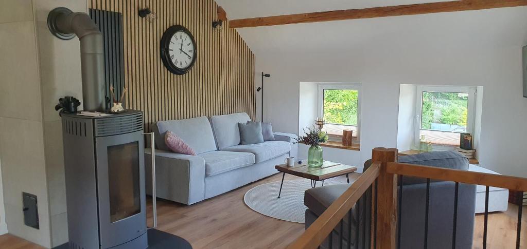een woonkamer met een bank en een klok aan de muur bij Cottage MaarBurg in Ulmen