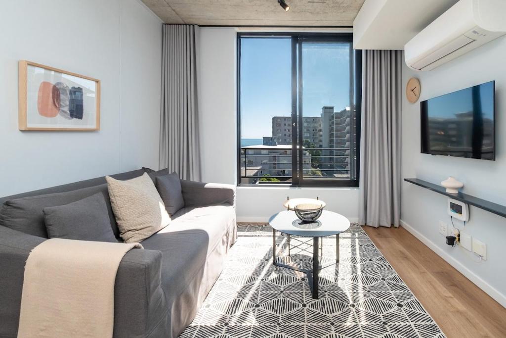 een woonkamer met een bank en een tafel bij Cosy Oasis in the heart of Sea Point in Kaapstad
