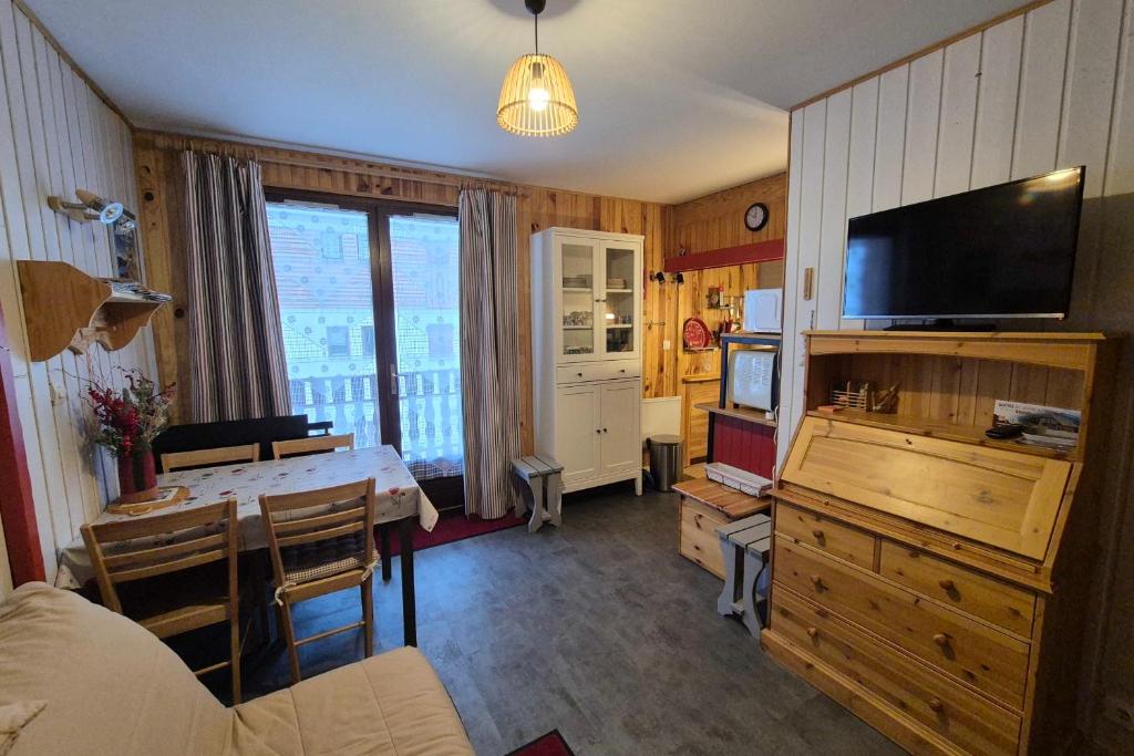 a living room with a dining table and a television at Appartement idéal famille - pied des pistes in Les Déserts