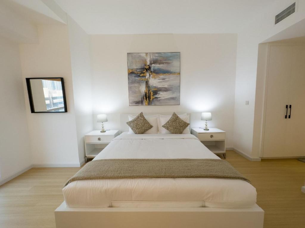 a white bedroom with a large bed and two night stands at Bel appartement Dubai marina in Dubai