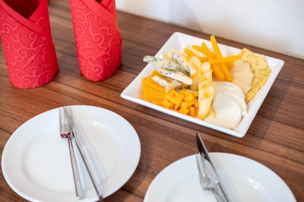 a table with a plate of cheese and french fries at Bükkös Hotel & Spa in Szentendre