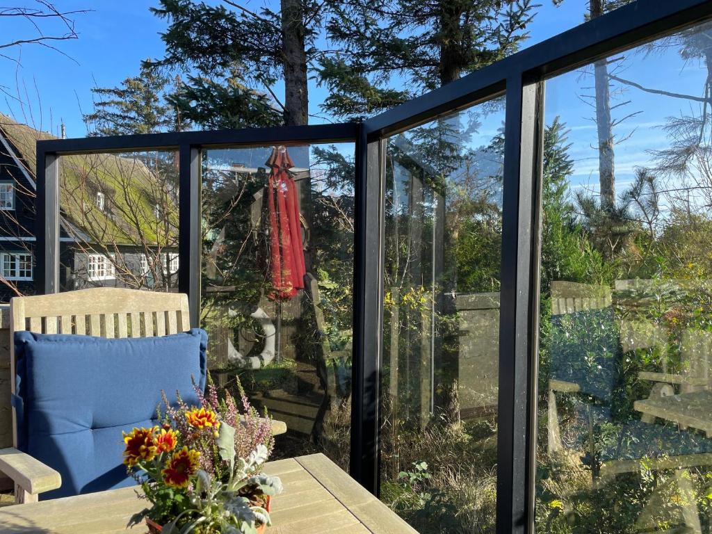 a conservatory with sliding glass doors and a table with flowers at Huus Lüttenblick Whg Kajüte in Südstrand