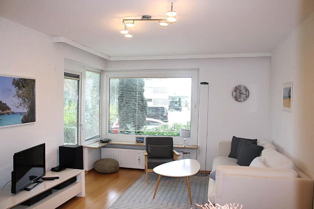 a living room with a white couch and a tv at Hanseat II App112 Ostseeglanz in Grömnitzerhagen