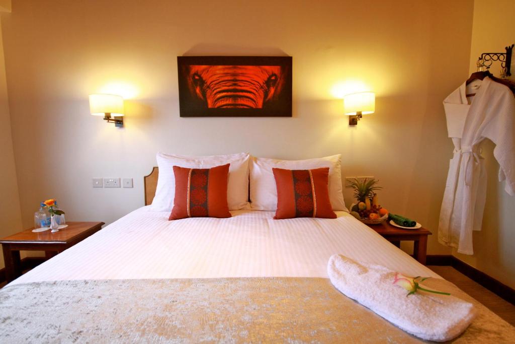 a bedroom with a large white bed with orange pillows at The Ark Lodge in Nyeri