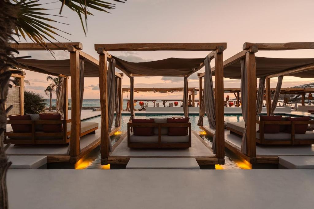a resort with three beds with the ocean in the background at Branco Mykonos in Platis Gialos