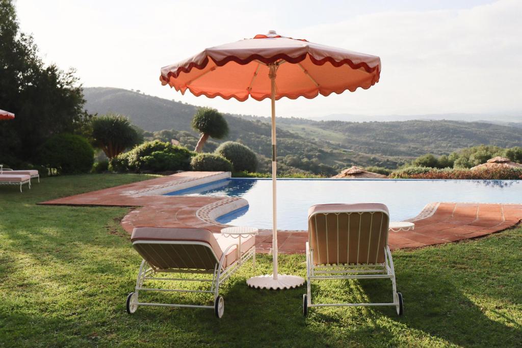 two chairs and an umbrella next to a pool at Cortijo Genesis in Gaucín