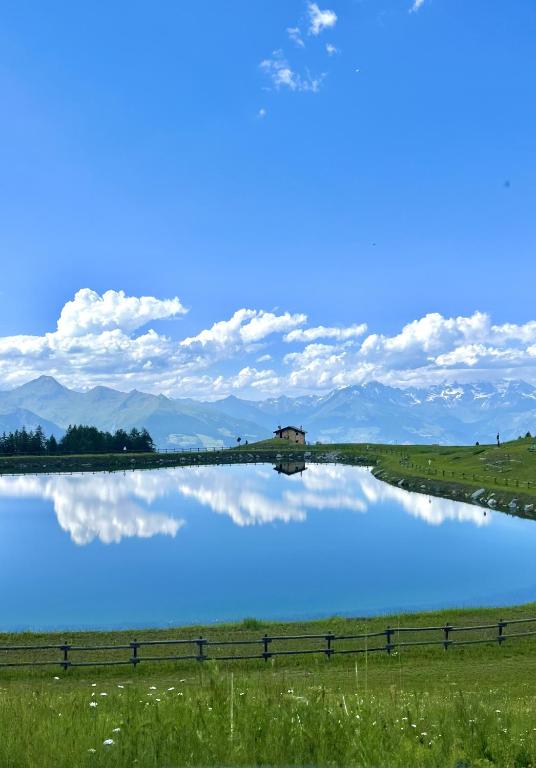 a blue lake in a field with clouds in the sky at Alpine Dream House - Chalet in Gressan
