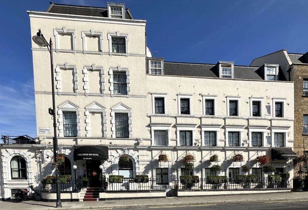 a large white building on the corner of a street at Kings Cross Inn Hotel in London