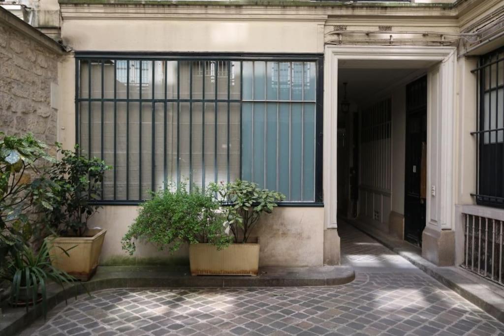 un bâtiment avec deux plantes en pot devant une porte dans l'établissement Lofts Marais Reaumur, à Paris