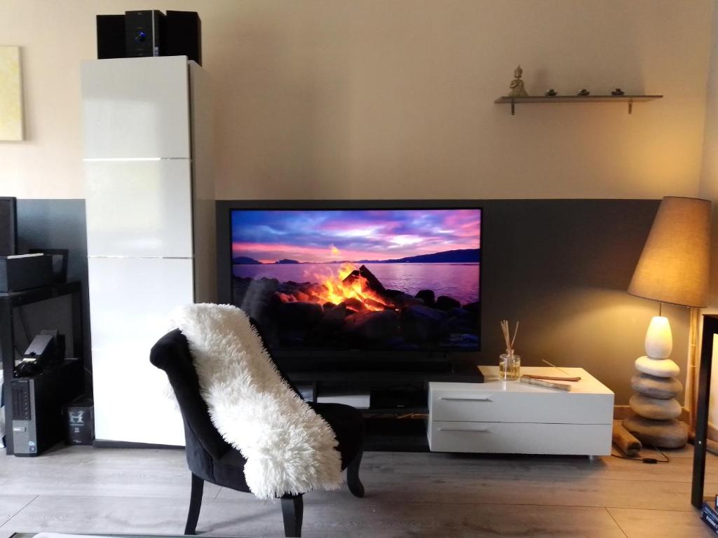 un salon avec une télévision et une chaise dans l'établissement Location T5 Cluses 100 M2, à Cluses