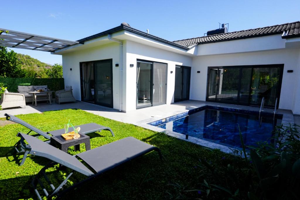 Un patio trasero con piscina y una casa. en Villa Nature, en Ortaca