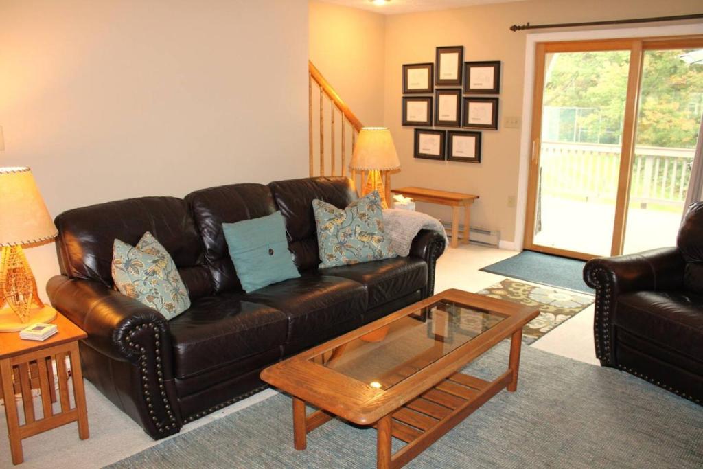 a living room with a leather couch and a coffee table at The White Mountain Escape in Woodstock