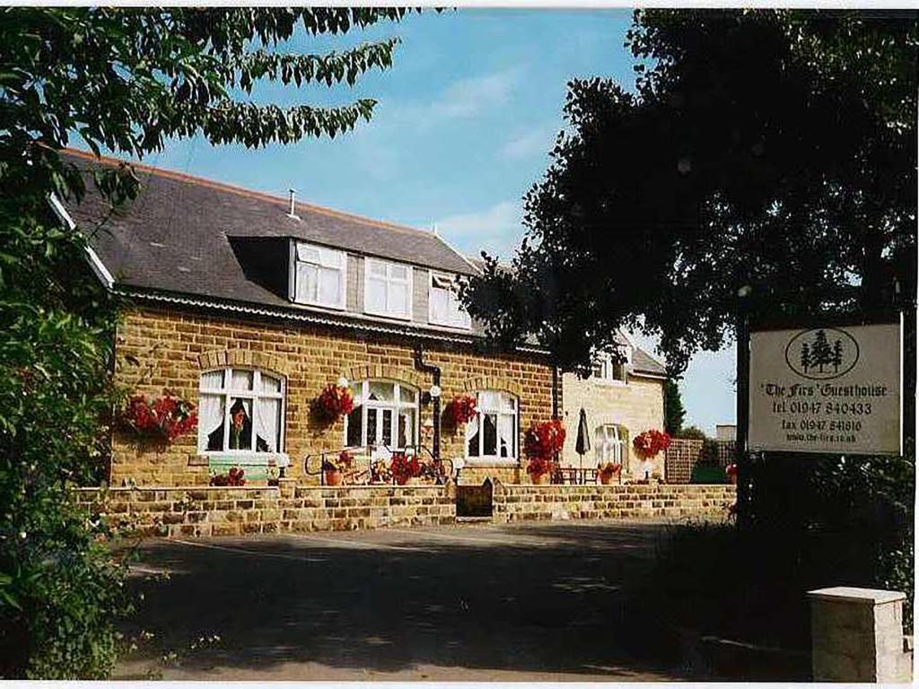 a brick building with a man in the window at The Firs Guesthouse in Runswick