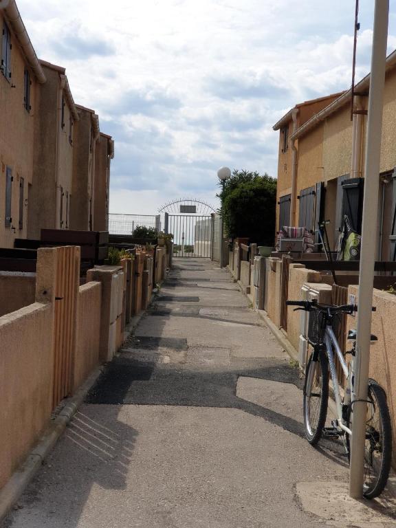 un vélo garé sur un trottoir à côté d'une clôture dans l'établissement appartement bord de mer, à Frontignan