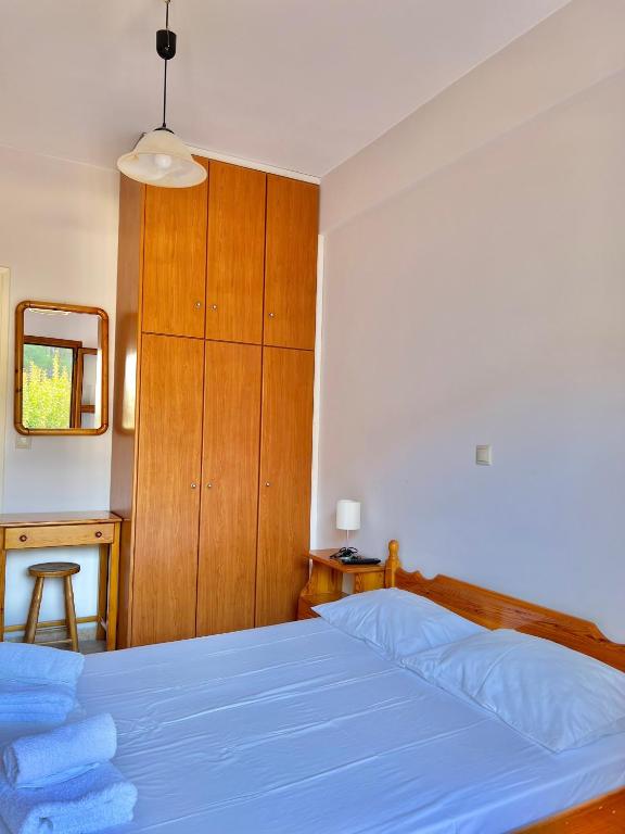 a bedroom with a blue bed and a wooden cabinet at Marinos Studios and Apartments in Gialiskari