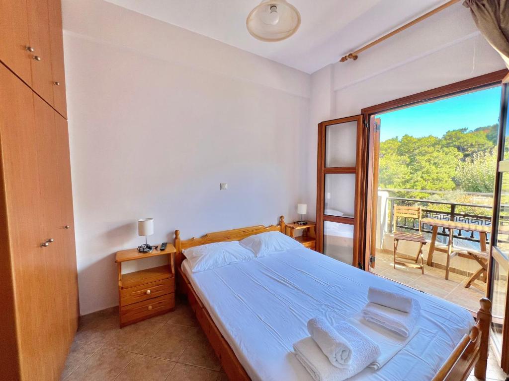 a bedroom with a bed and a large window at Marinos Studios and Apartments in Gialiskari